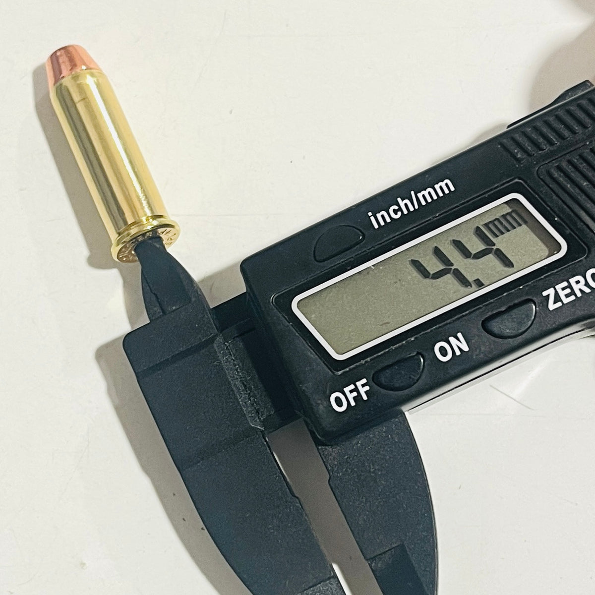 Digital caliper reading 4.4 mm in the empty primer pocket of a deprimed brass 38 Special spent  case with a copper flat nose bullet