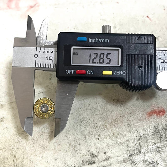 Digital caliper measuring the diameter of a 44 Magnum brass bullet slice showing 12.85 mm