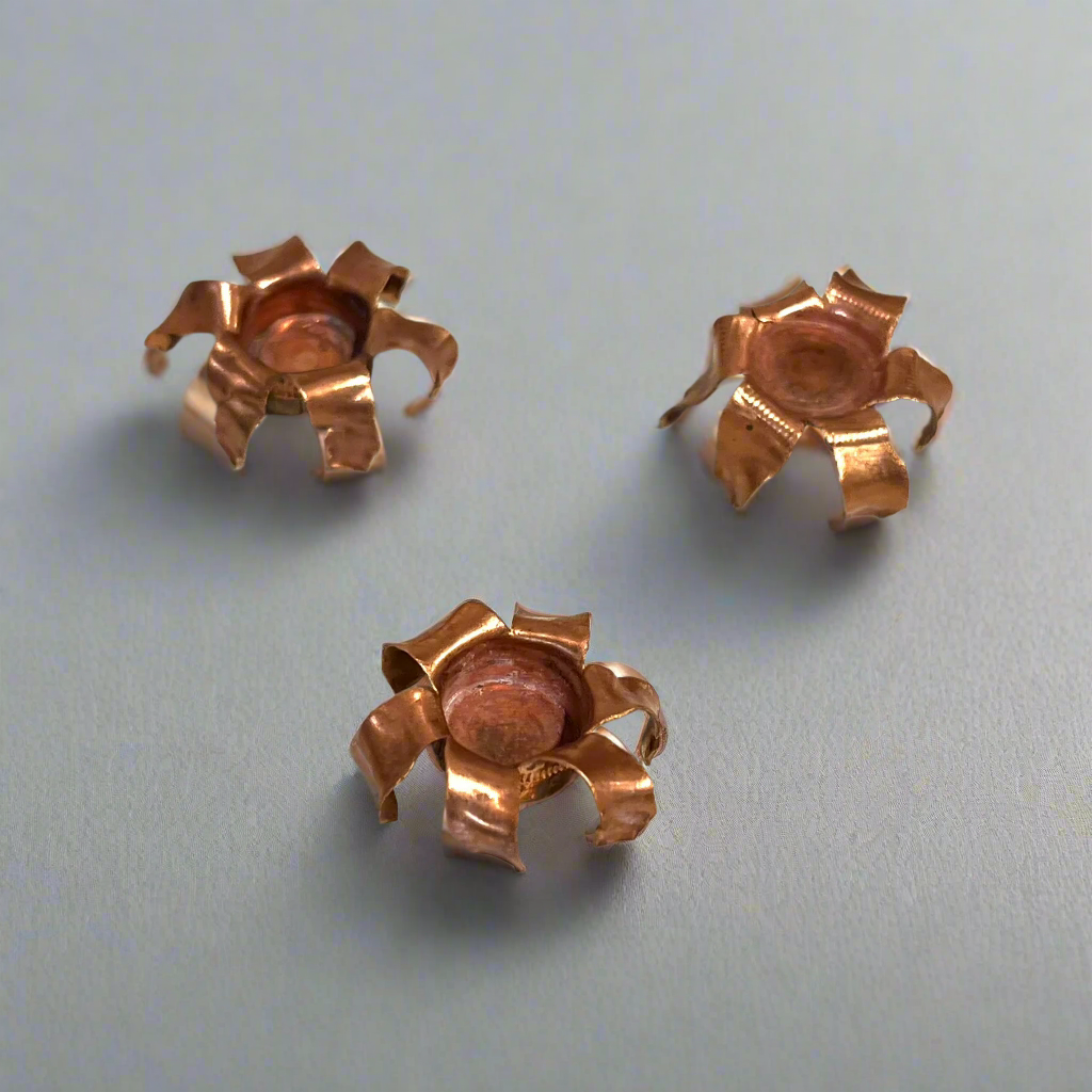 Three expanded copper bullet jacket blossoms on a gray background