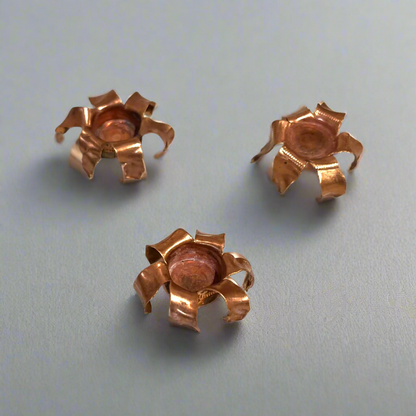 Three expanded copper bullet jacket blossoms on a gray background