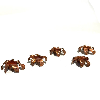 Five expanded copper bullet jacket blossoms scattered on white background