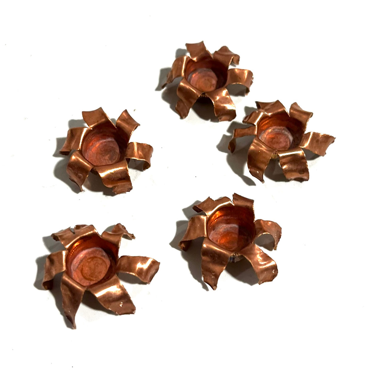 Five expanded copper bullet jacket blossoms scattered on white background