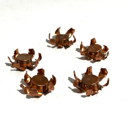 Five expanded copper bullet jacket blossoms each with a flattened lead core visible in the center, scattered on white background