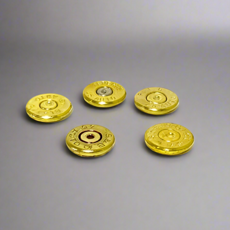 Five gold brass casing slices spread out on a gray background, one showing a silver primer center.