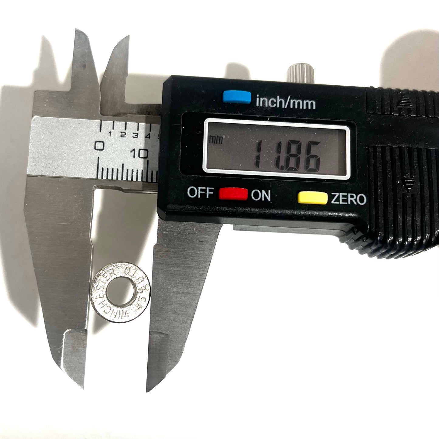 A digital caliper measuring the diameter of a deprimed Winchester 45 Auto nickel spent cartridge slice, reading 11.86 mm.