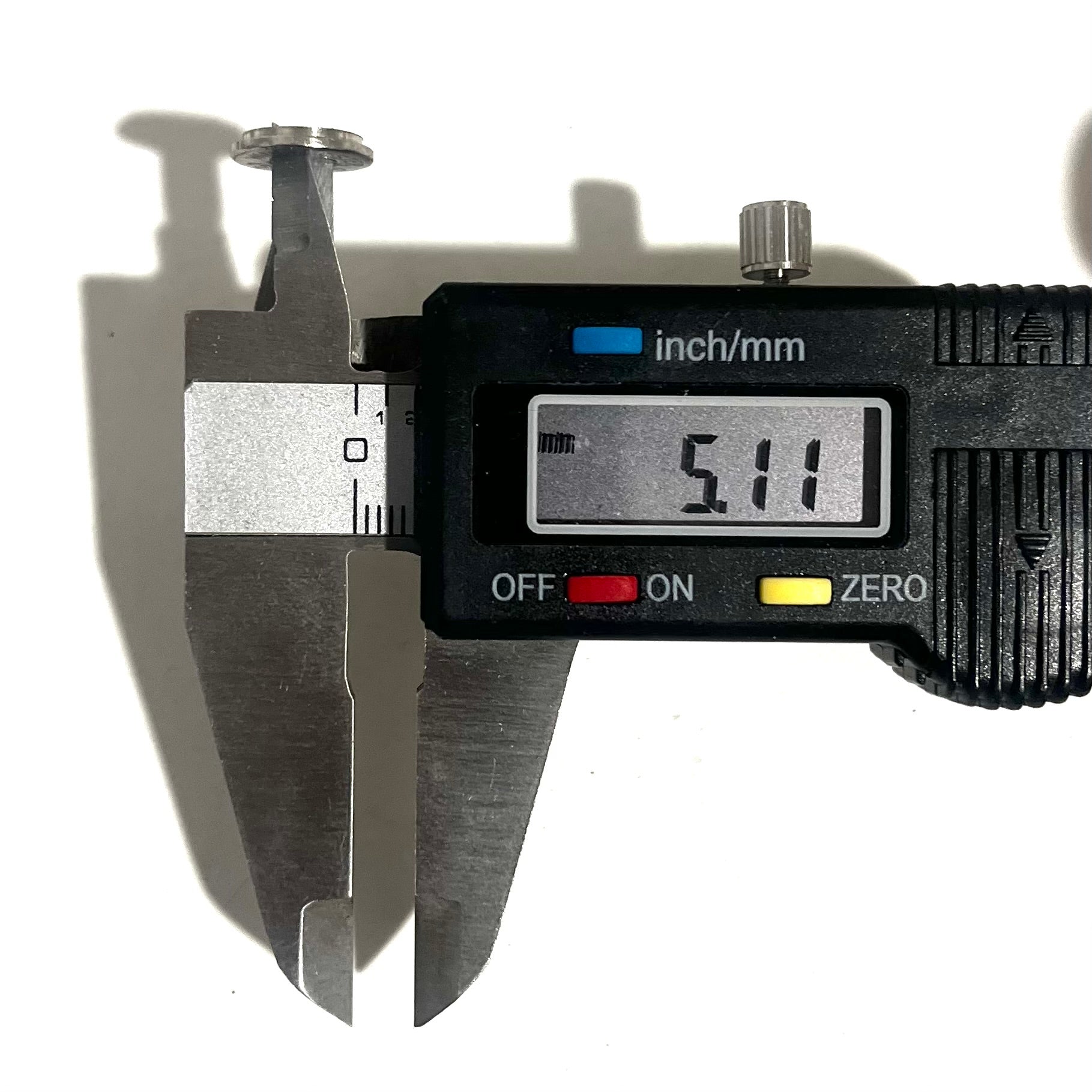 A digital caliper measuring the thickness of a deprimed nickel shell slice, showing a readout of 5.11 mm.