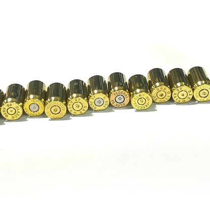A row of gold 45 ACP brass on their sides, showing mixed headstamps spent primers including Winchester, Federal, and S&B.