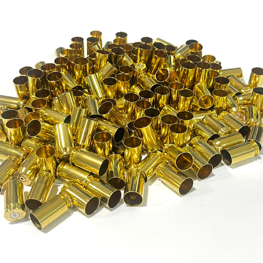 Large bulk pile of once fired gold 45 ACP brass shells, case mouths facing up, a few rims visible at the edges.