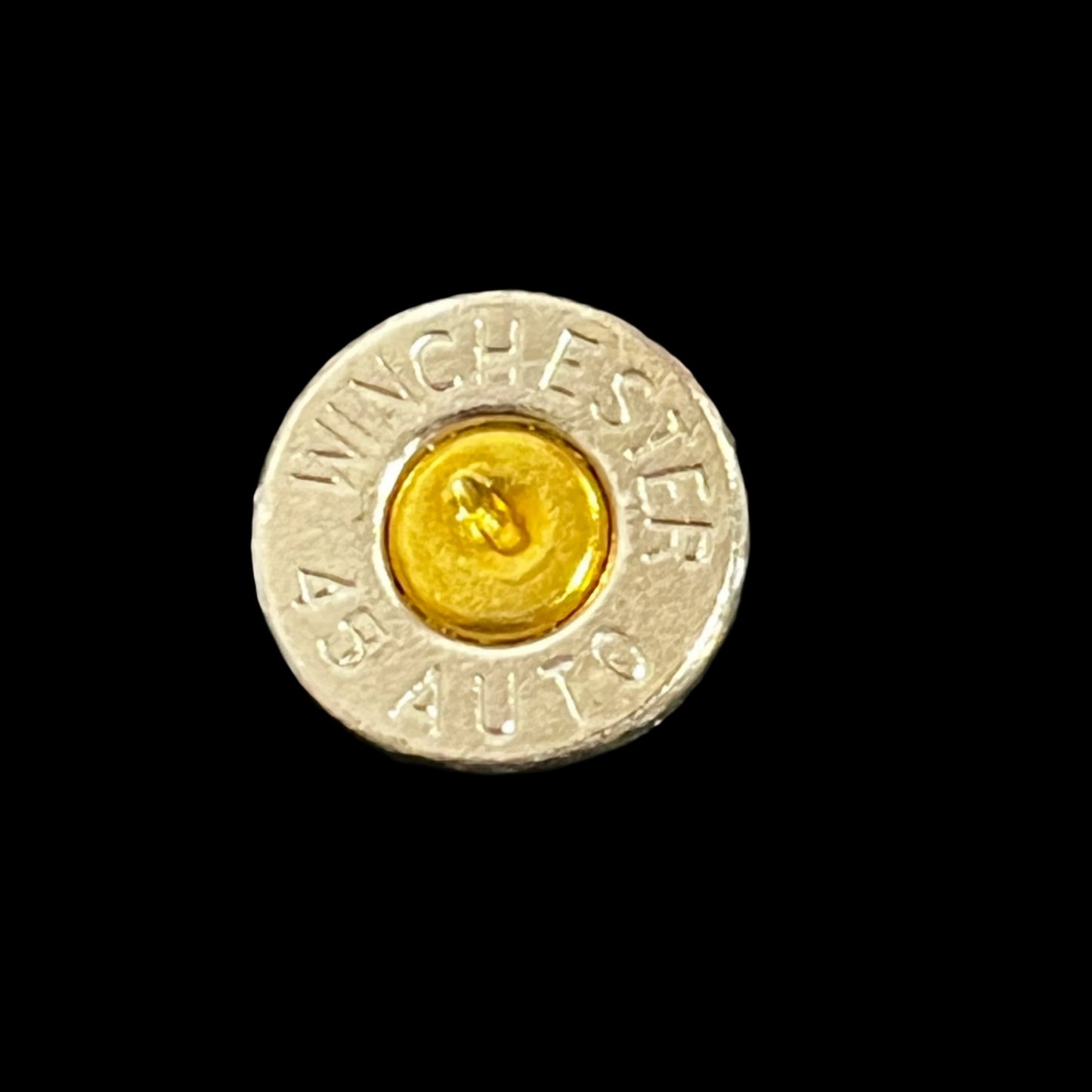 Close-up of a nickel 45 ACP bullet slice with a gold primer, engraved Winchester 45 Auto headstamp, on a black background