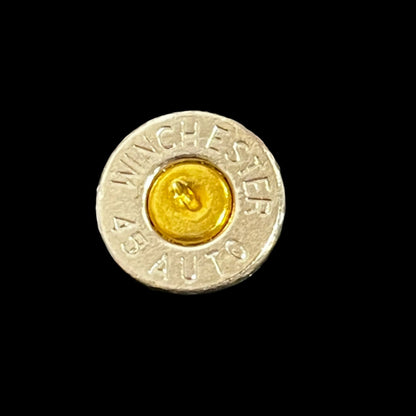 Close-up of a nickel 45 ACP bullet slice with a gold primer, engraved Winchester 45 Auto headstamp, on a black background