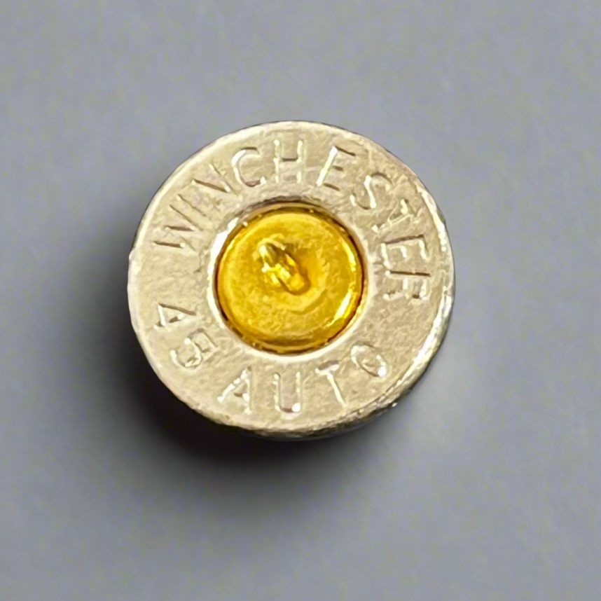 Close-up of a nickel 45 ACP bullet slice with a gold primer, engraved Winchester 45 Auto headstamp