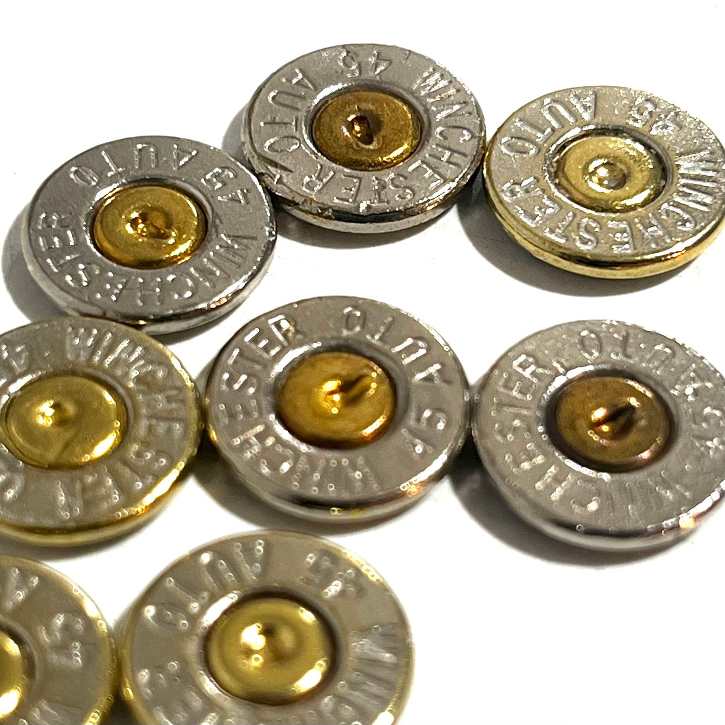 Close-up of 8 nickel 45 ACP bullet slices with gold primers, engraved Winchester 45 Auto headstamps