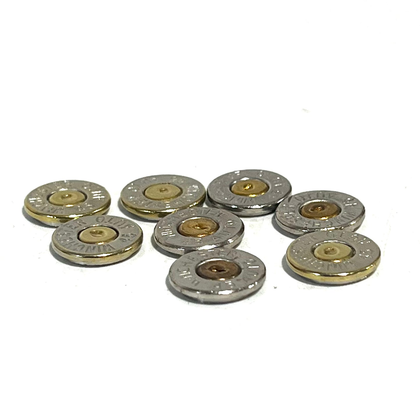 8 nickel 45 ACP bullet slices with gold and copper primers, engraved Winchester 45 Auto headstamps, arranged in a cluster