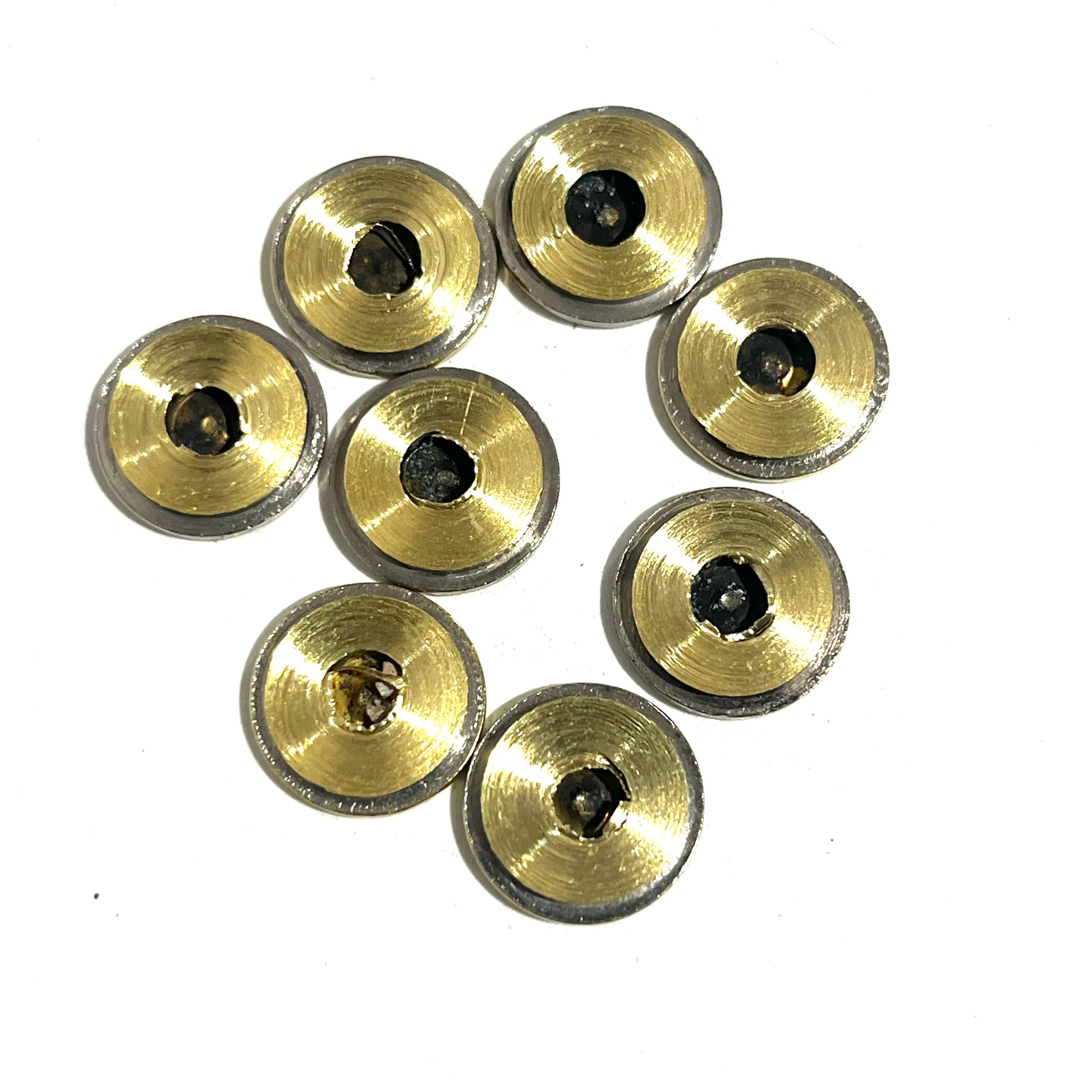 8 nickel 45 ACP bullet slices viewed from the reverse side showing brass primer pockets