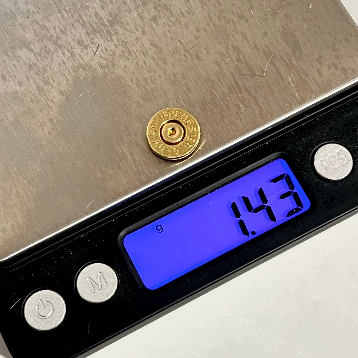Gold 45 ACP Winchester bullet slice on a digital scale reading 1.43 grams
