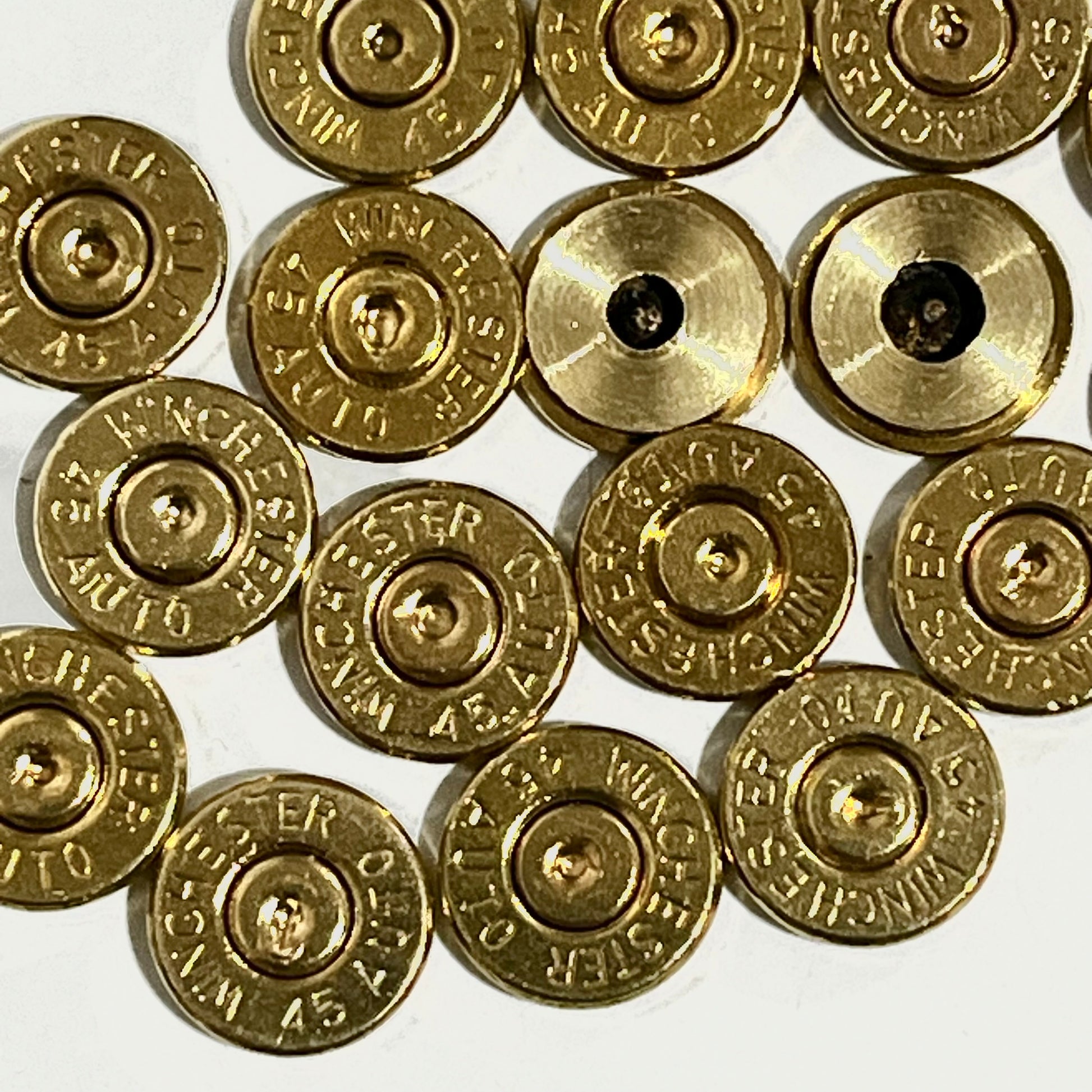 Close-up of gold 45 ACP brass bullet slices with Winchester headstamps, some with drilled holes