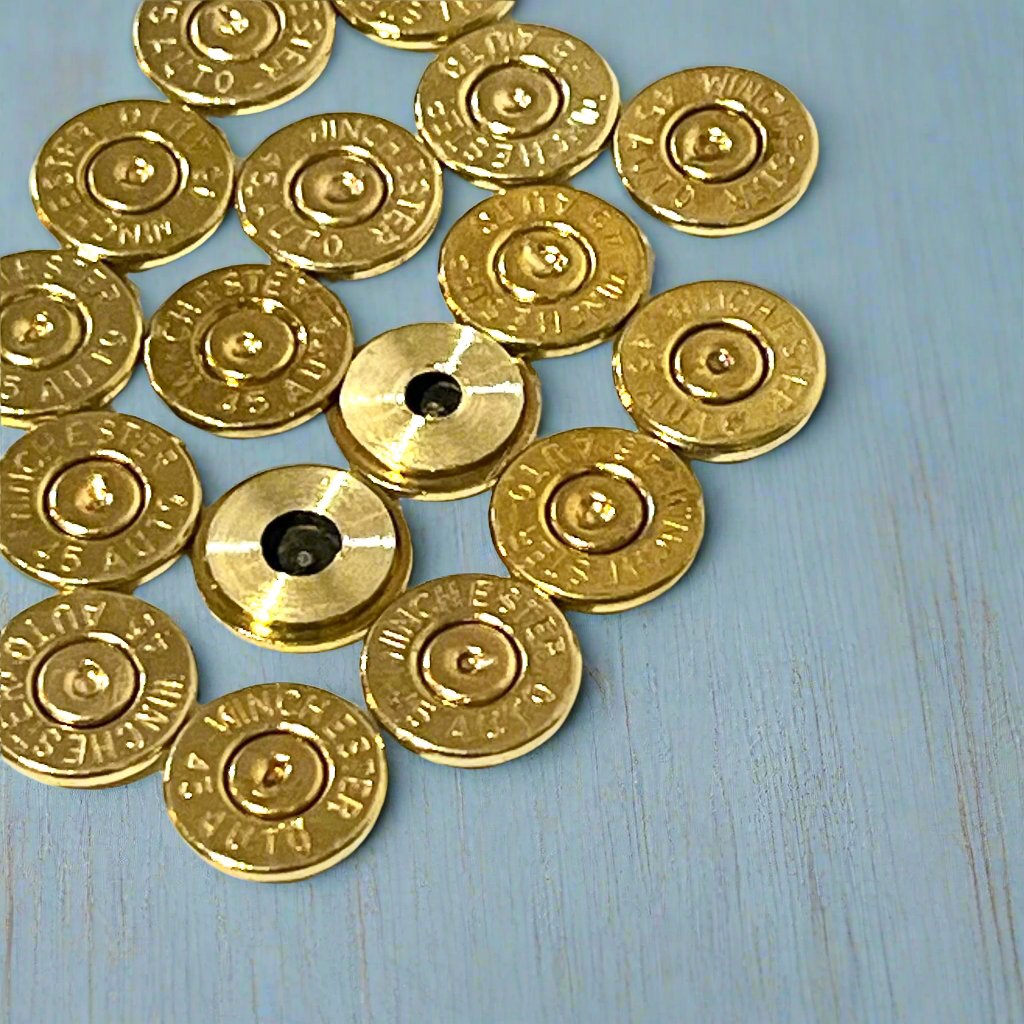 Group of gold 45 ACP brass bullet slices with Winchester headstamps, some with visible drilled holes, arranged in a cluster