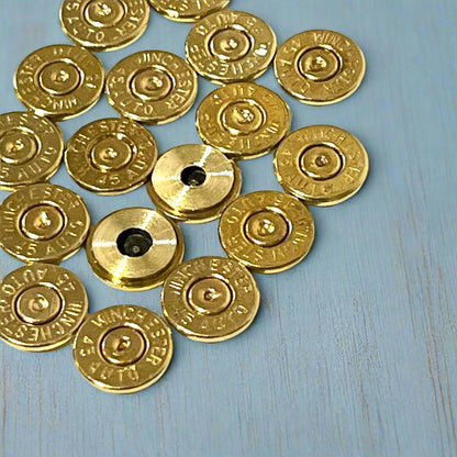 Group of gold 45 ACP brass bullet slices with Winchester headstamps, some with visible drilled holes, arranged in a cluster
