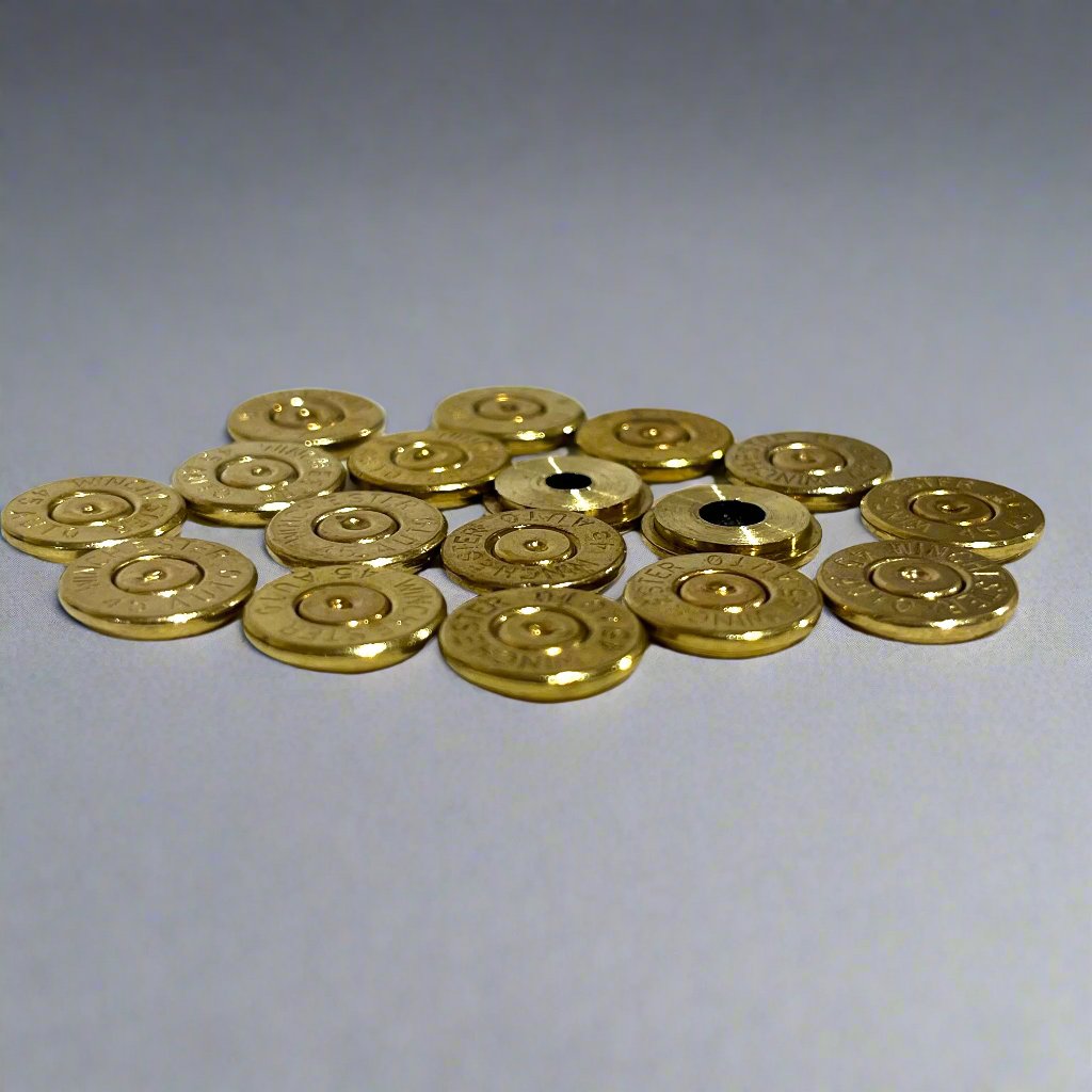 Group of gold 45 ACP brass bullet slices with Winchester headstamps, some with visible drilled holes, arranged on a gray surface