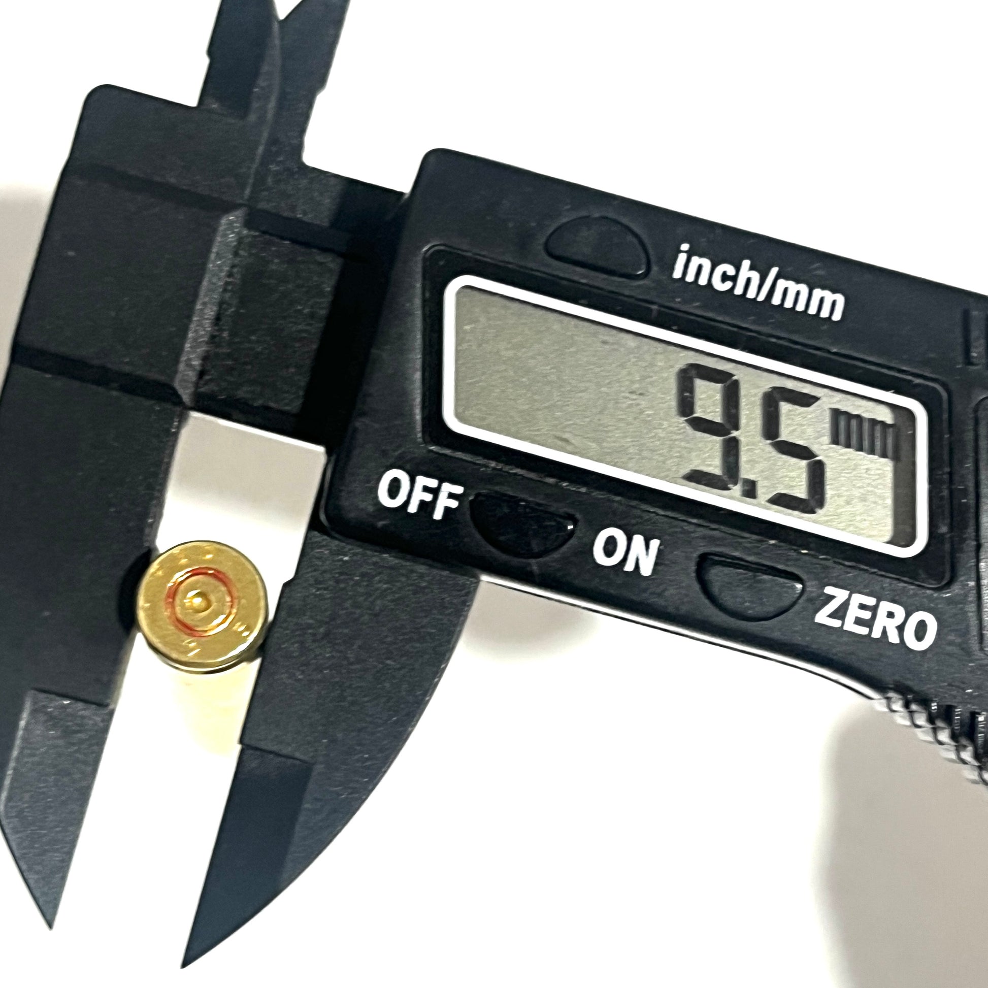 A digital caliper measures the rim of a gold .223/5.56 casing, with the display reading 9.5 mm.