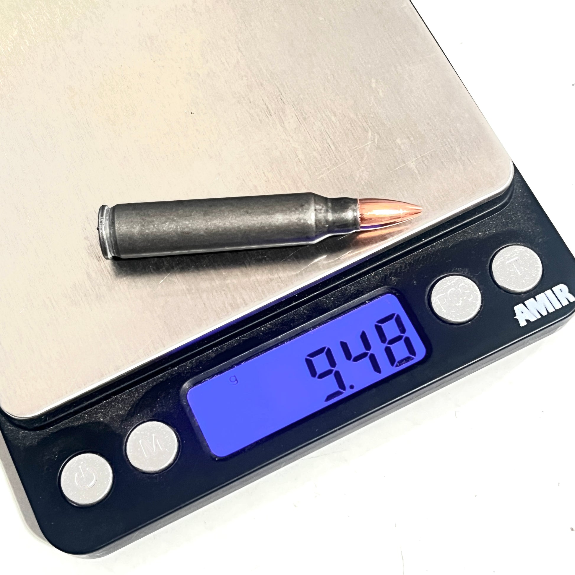 A single gray .223/5.56 cartridge rests on a digital scale, with the display reading 9.48 grams.