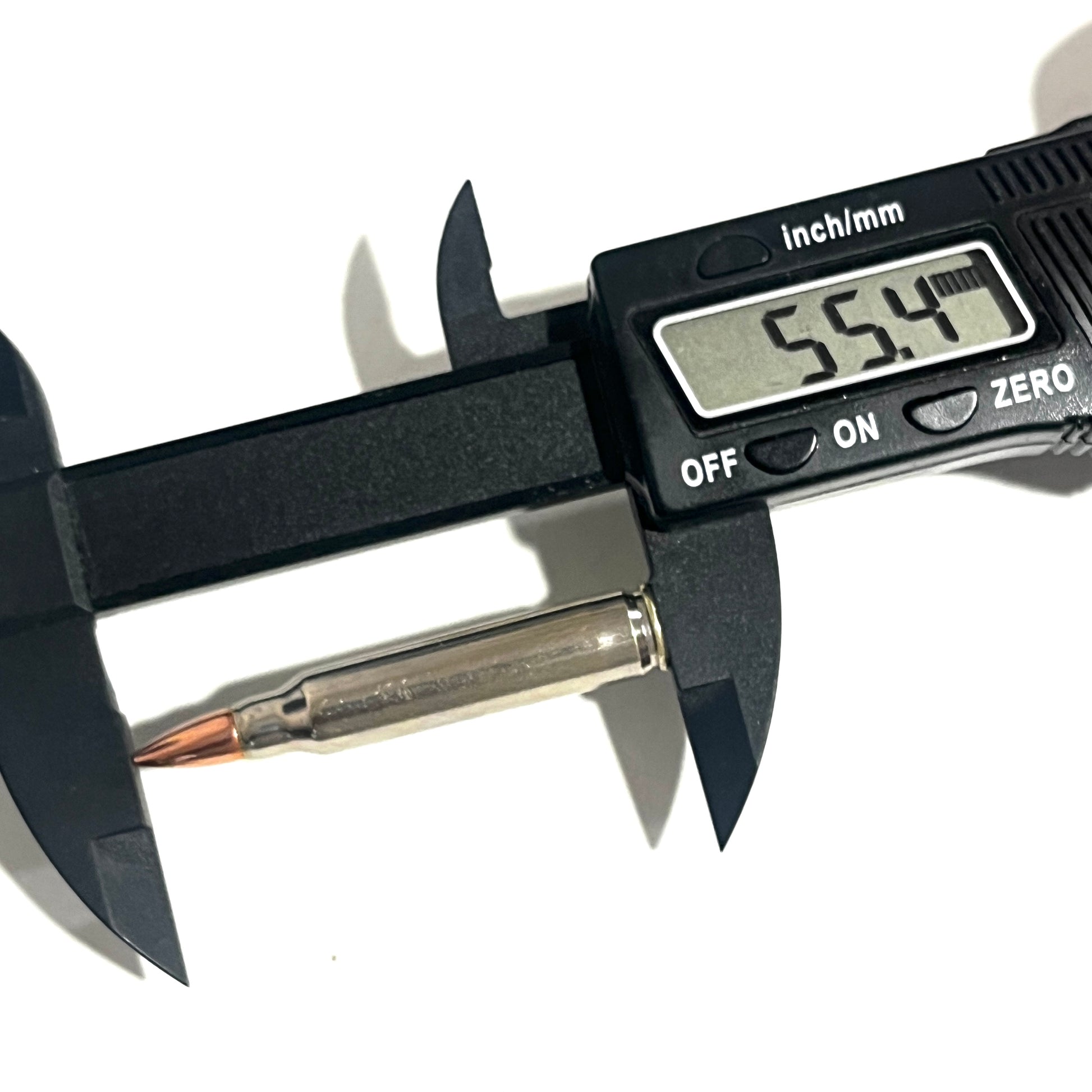 A digital caliper measures a silver .223/5.56 shell, with the display reading 55.4 mm in length.