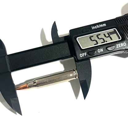 A digital caliper measures a silver .223/5.56 shell, with the display reading 55.4 mm in length.
