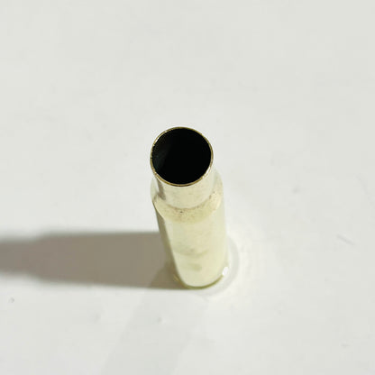 Overhead view into the open mouth of a polished .50 BMG brass case standing on white