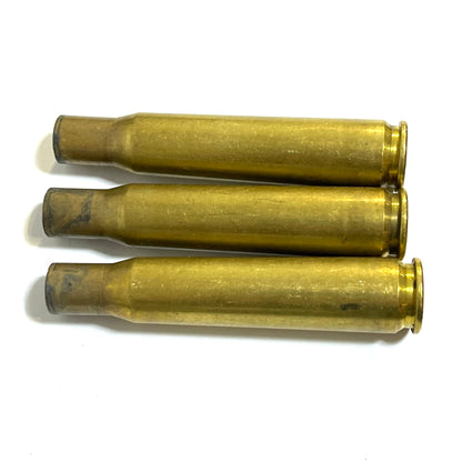 50 Caliber BMG fired raw brass shells on white background horizontal 