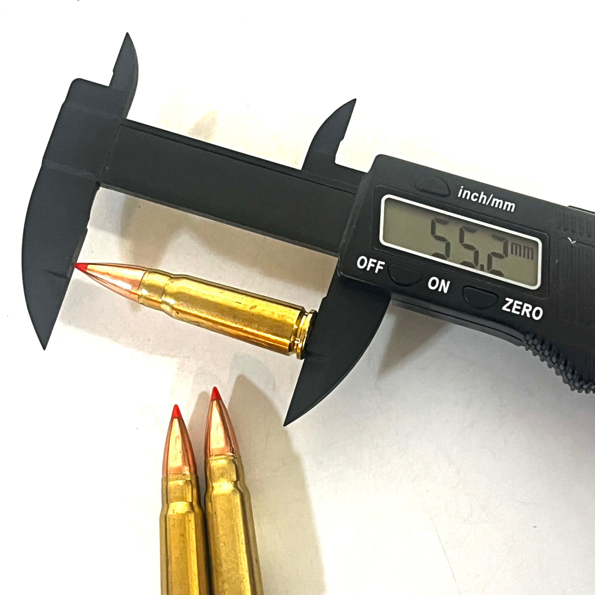 Digital caliper measuring a brass 7.62x39 dummy round's length at 55.2 millimeters, with two more rounds beside it