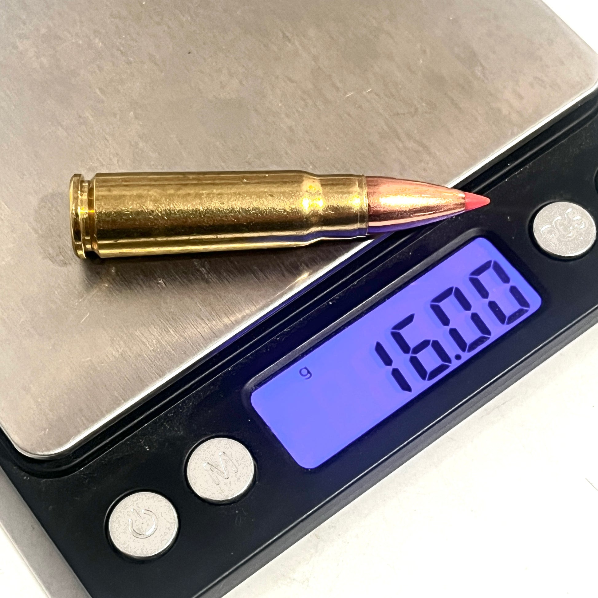 Brass 7.62x39 dummy round with a red-tipped bullet on a digital scale reading 16.00 grams
