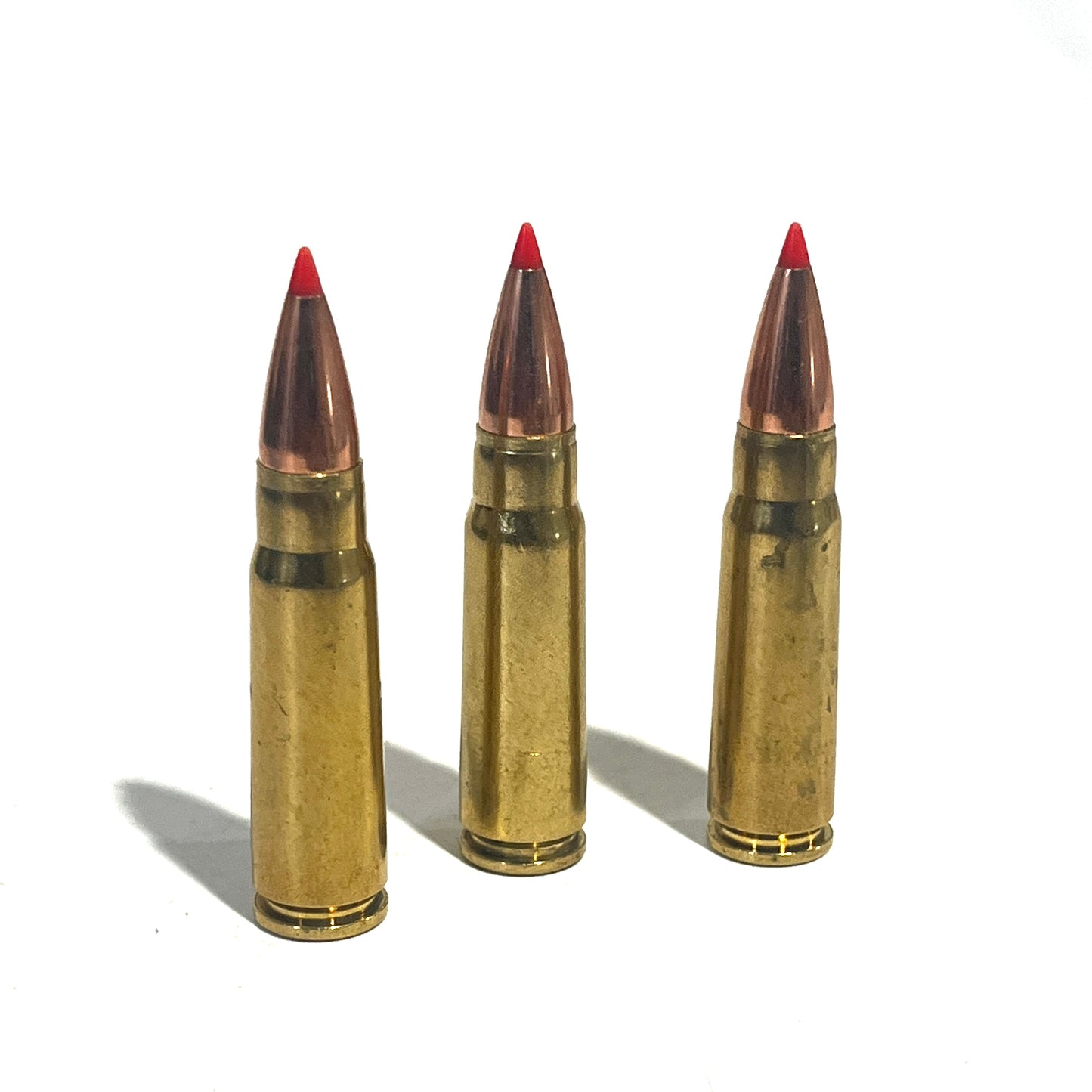 3 brass 7.62x39 dummy rounds with red-tipped bullets standing upright on a white background