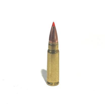 Single brass 7.62x39 dummy round with a red-tipped bullet, standing upright on a white background