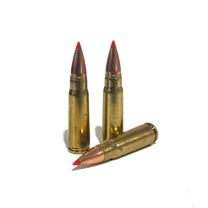 3 brass 7.62x39 dummy rounds with red-tipped bullets, two standing and one lying diagonally, on a white background