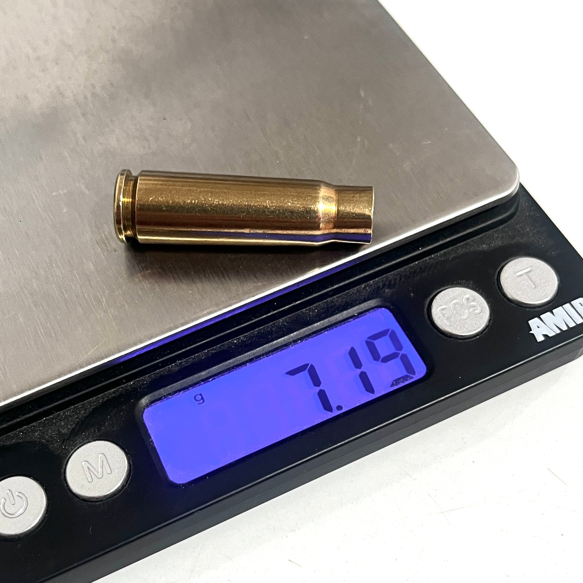 Spent brass shell resting on a digital scale, with the display showing a weight of 7.19 grams.