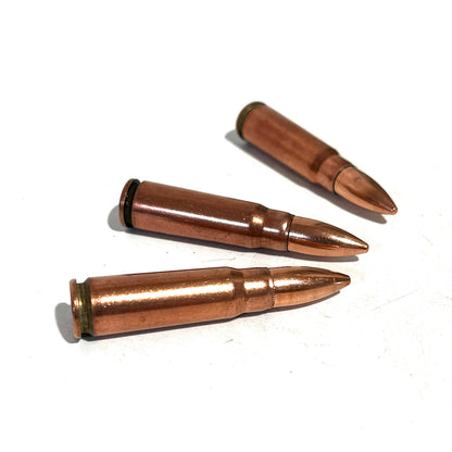 3 copper 7.62x39 dummy rounds lying on a white background at an angle