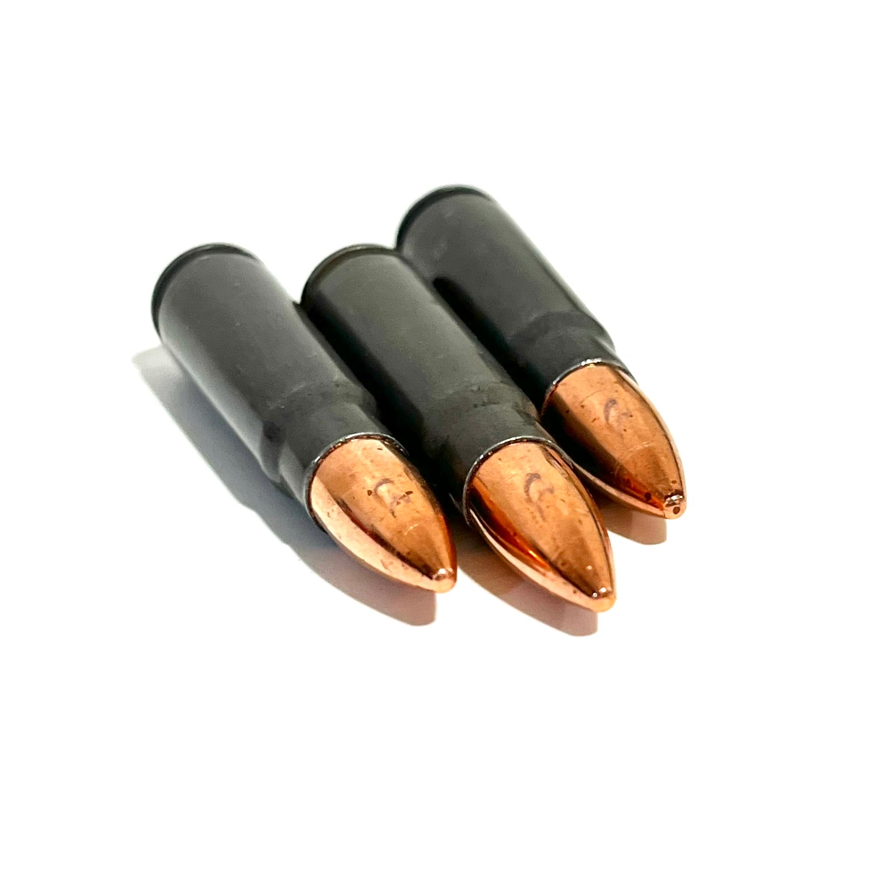 Close-up of three dummy 7.62x39 steel shells with copper bullet tips angled toward the camera.