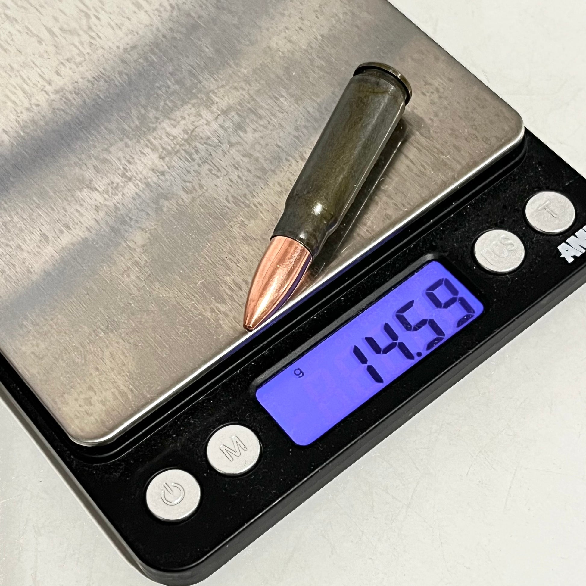 A gray steel 7.62x39 dummy shell with a copper bullet resting on a digital scale reading 14.59 grams.