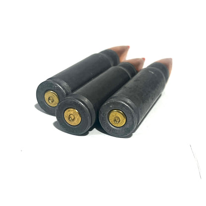 3 steel 7.62x39 dummy rounds with red-tipped bullets standing upright showing brass primers, viewed from the base