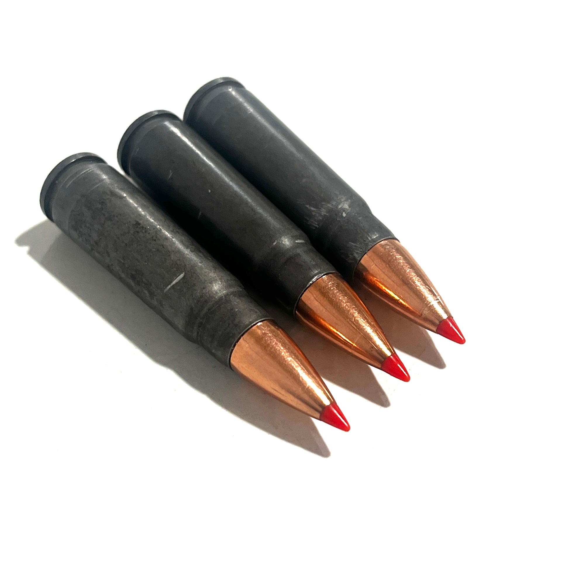3 steel 7.62x39 dummy rounds with red-tipped bullets lying at an angle on a white background