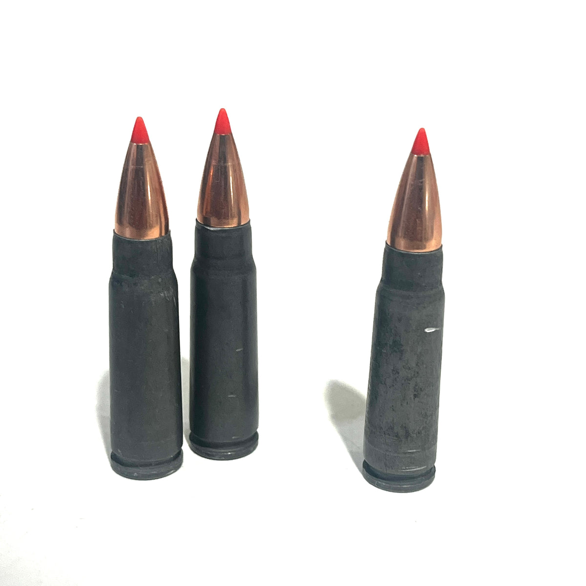 3 steel 7.62x39 dummy rounds with red-tipped bullets standing upright on a white background