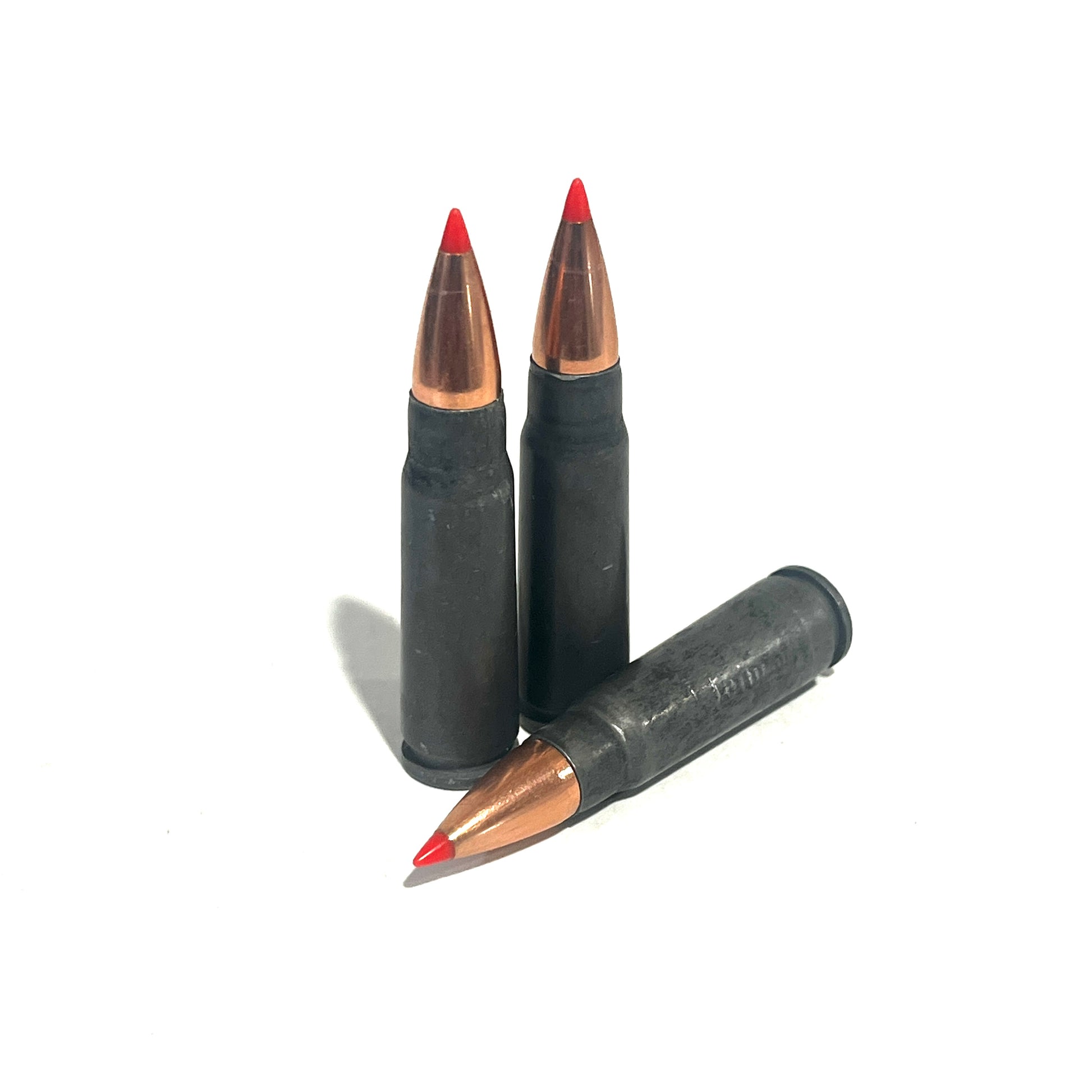 3 steel 7.62x39 dummy rounds with red-tipped bullets, two standing and one lying diagonally, on a white background