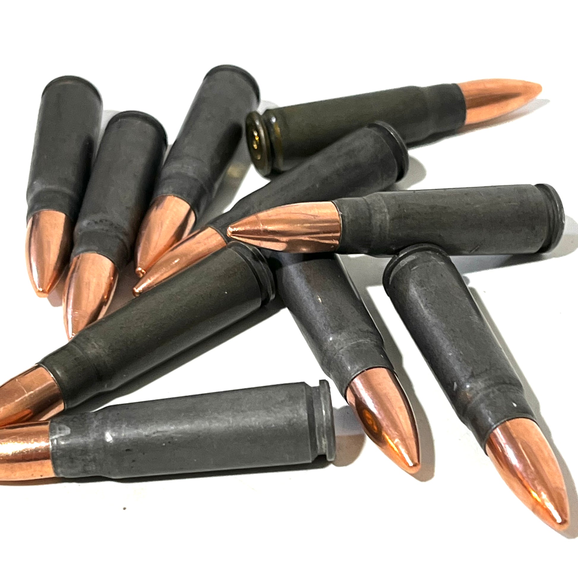 A scattered pile of steel 7.62x39 cartridges with copper-tone bullets fanned across a white background.