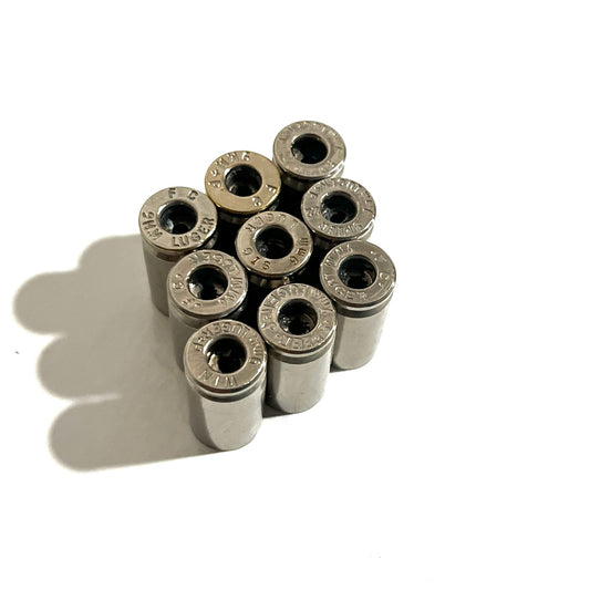 Nine deprimed 9mm nickel casings clustered together, headstamps visible on open case heads