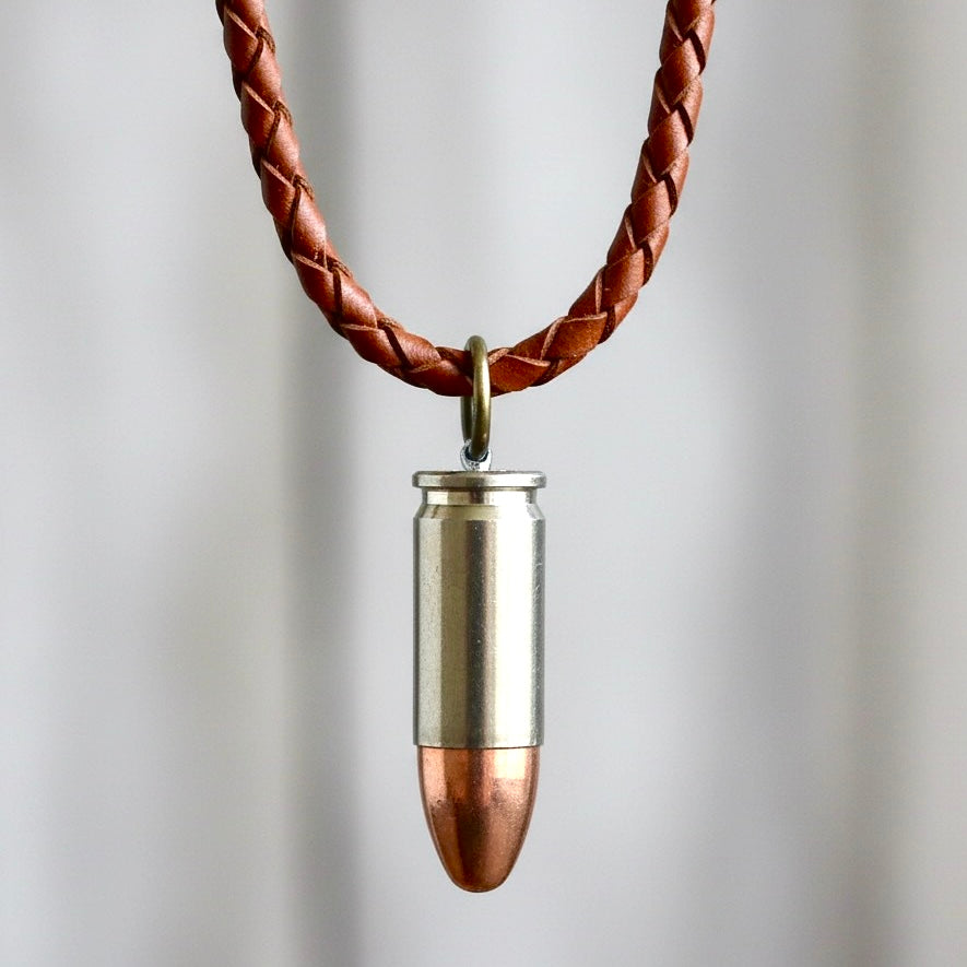 Authentic 9mm nickel dummy bullet casing fashioned into a pendant on a braided brown leather cord.