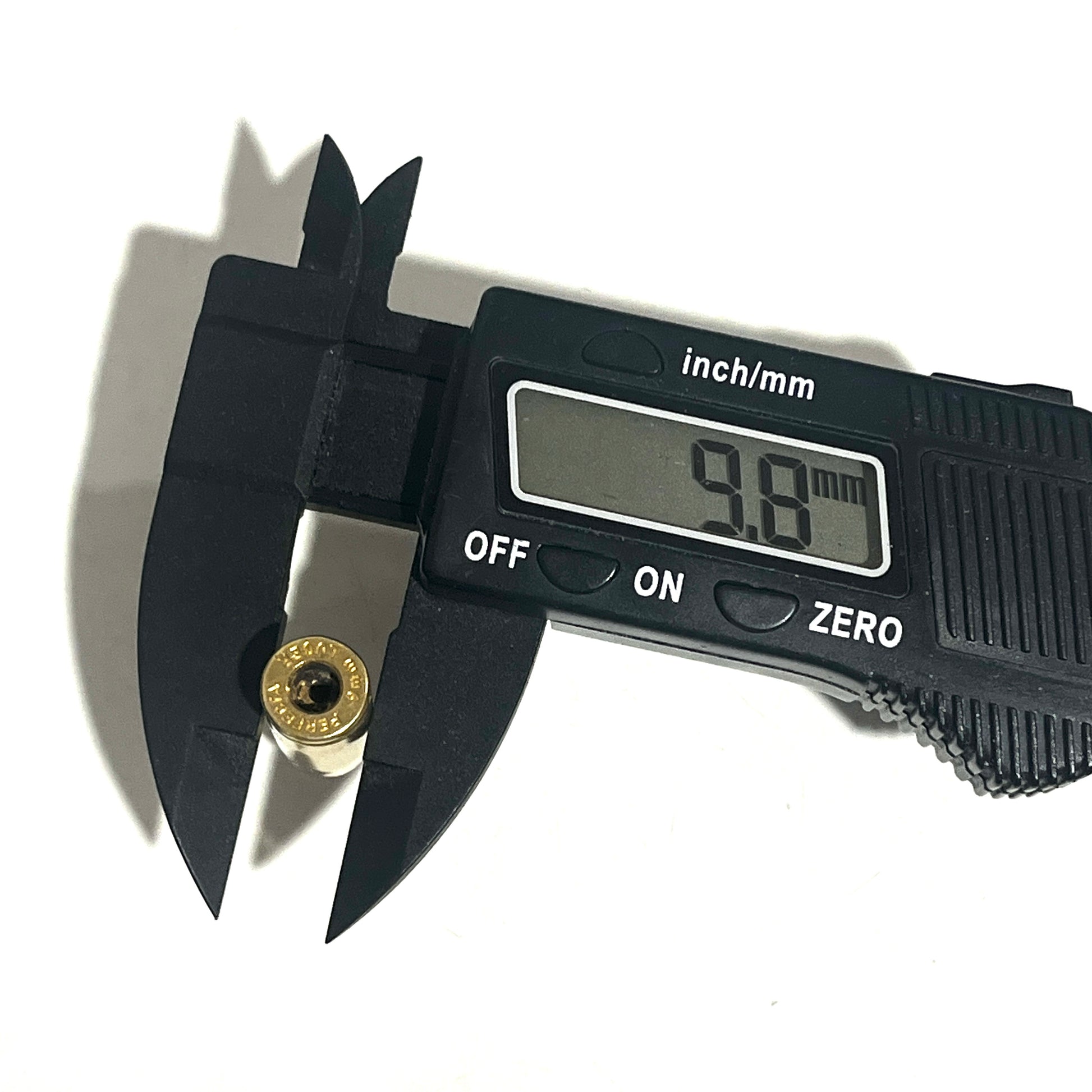 Black digital caliper measuring the rim diameter of a 9mm dummy round casing, showing a display reading of 9.8 mm.