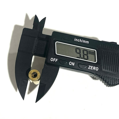Black digital caliper measuring the rim diameter of a 9mm dummy round casing, showing a display reading of 9.8 mm.