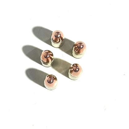 Top view of five 9mm dummy round copper bullets standing upright on a white background with shadows.