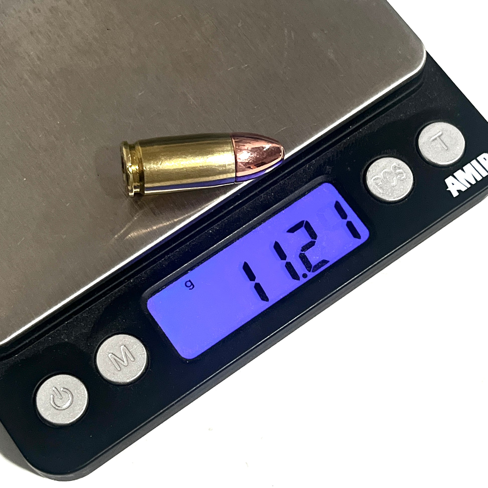 Digital scale displaying a weight of 11.21 grams for a single 9mm inert cartridge with a brass casing and copper bullet.