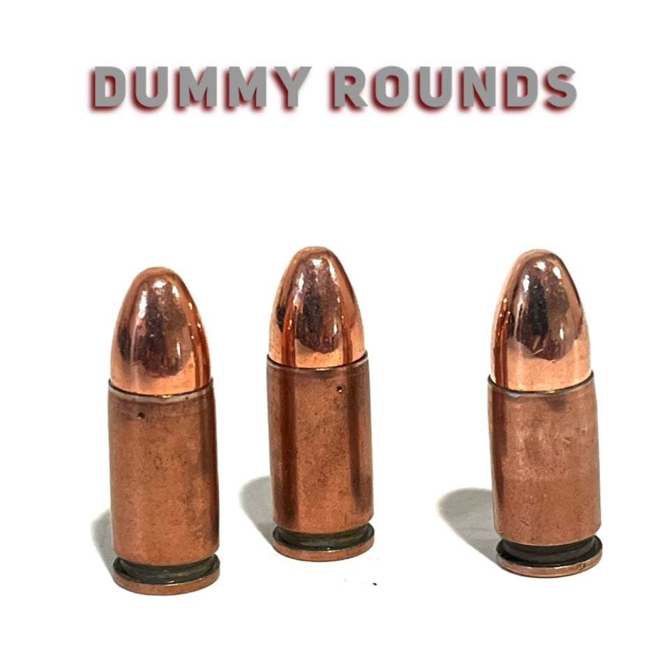 3 copper 9mm Luger dummy rounds with round nose bullets, standing upright under a Dummy Rounds text banner